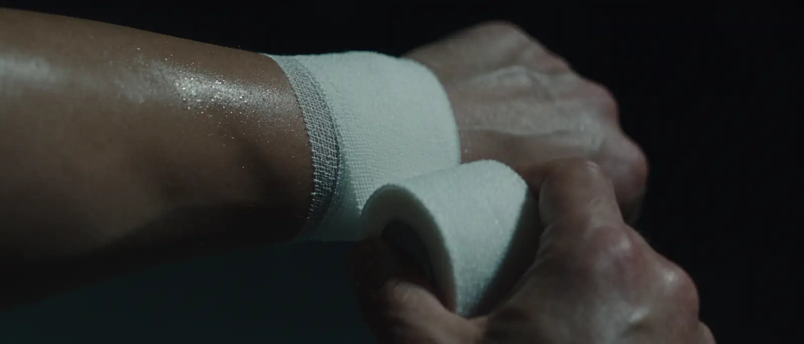 Hands wrapping athletic tape around a wrist.